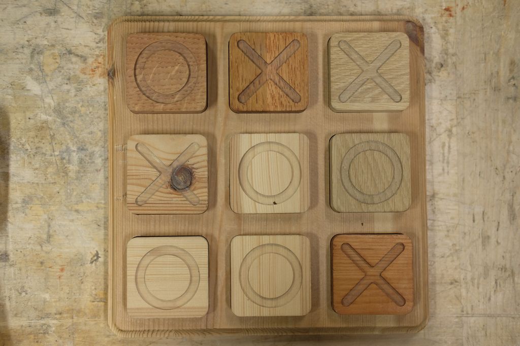 Firkanta brikker til tre-på-rad-spill, lagd av ulike treslag. Foto.