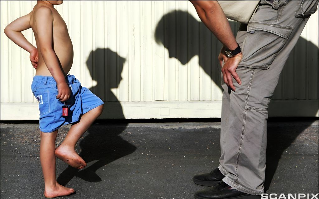 Far bøyer seg over og ser ned på sønnen. Foto.