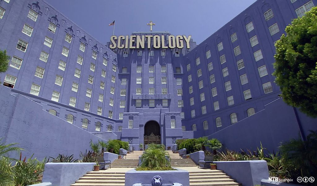 Stor, blå bygning. Øverst på bygningen står et kors og ordet "Scientology" med store bokstaver. Foto.