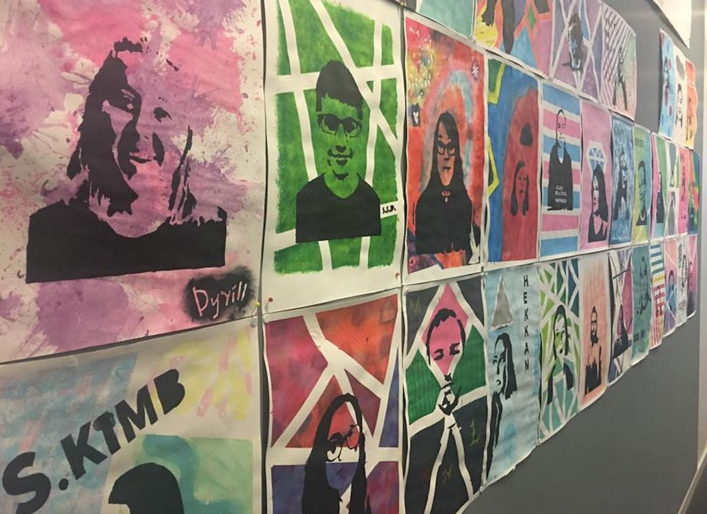 Foto av rundt tretti fargerike sjablongtrykk som henger utstilt på en vegg.