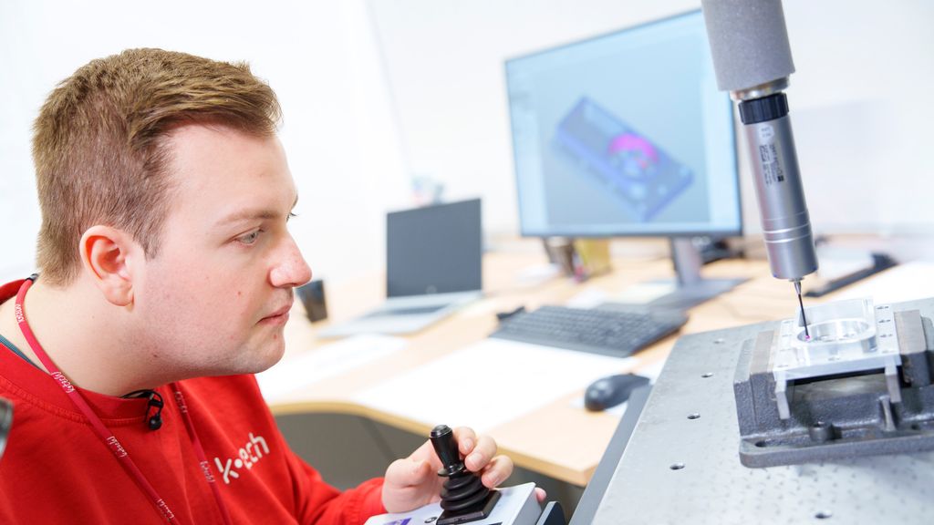 Person som sit konsentrert og styrer ein målespiss på ei maskin med ein joystick. Foto