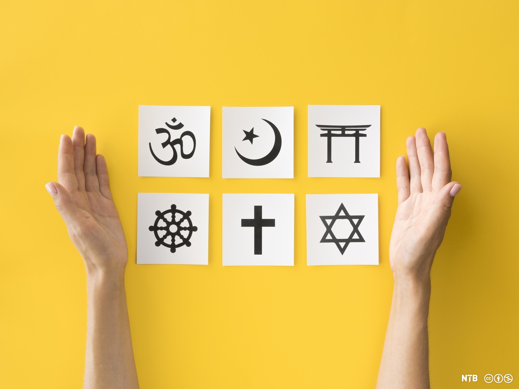 Seks religiøse symbol på kvar sin lapp med to armar på kvar side. Foto. 