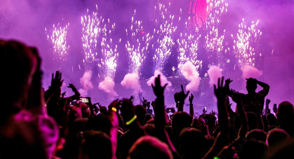 Publikum på en konsert strekker hendene i været mot scenen. Foto.
