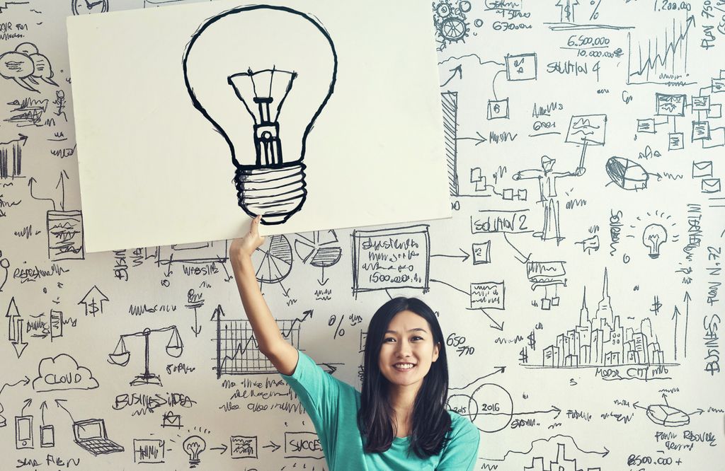 Kvinne held opp ein plakat med bilete av ei lyspære. Foto.