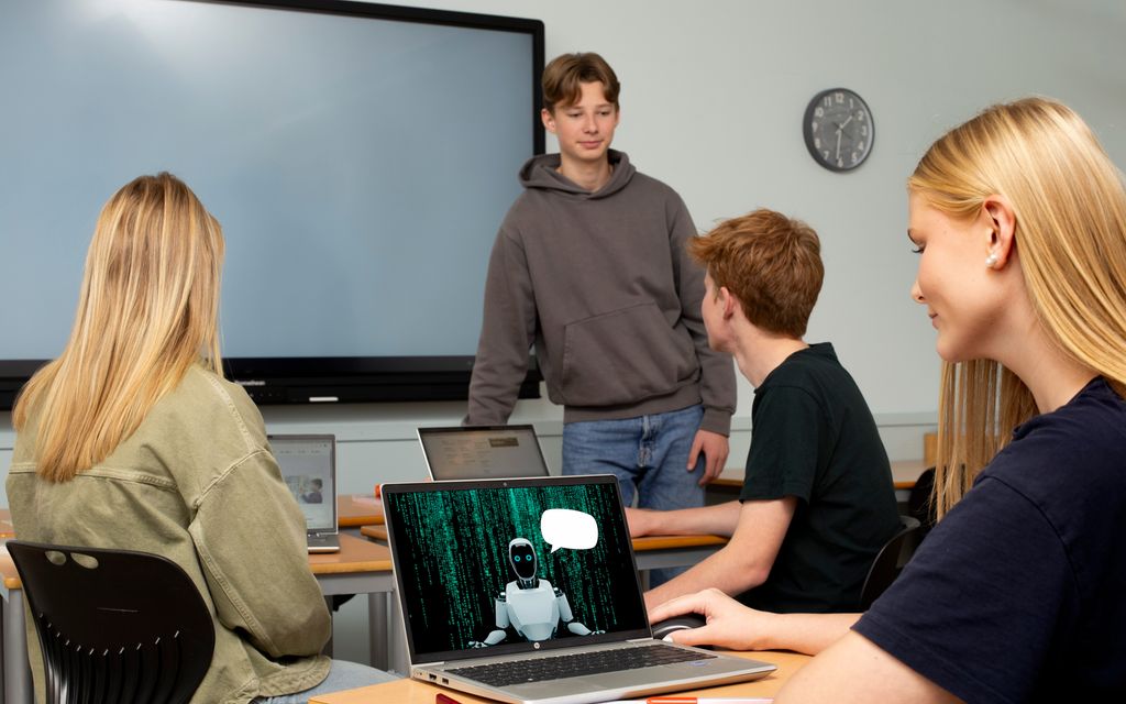 Elever i et klasserom. Jenta i forgrunnen har en praterobot med ei tom snakkeboble oppe på PC-skjermen sin. Foto.