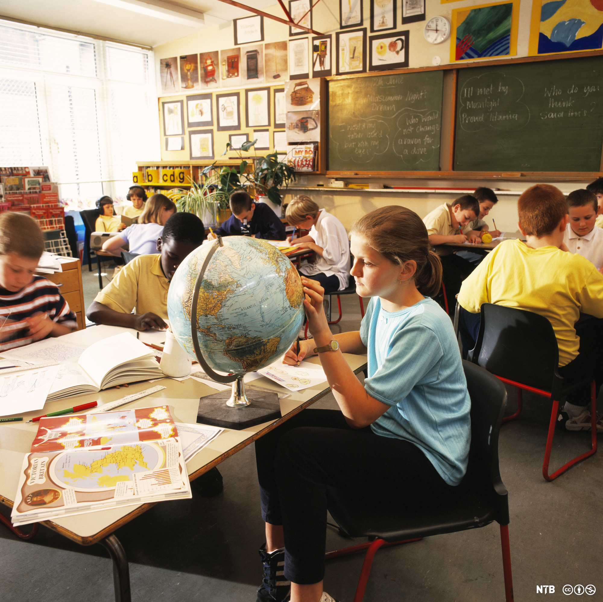 Schoolgirl looking at Africa on a globe. A book (lower left) is open at pages about Victorian Britain and the British Empire. Photo.