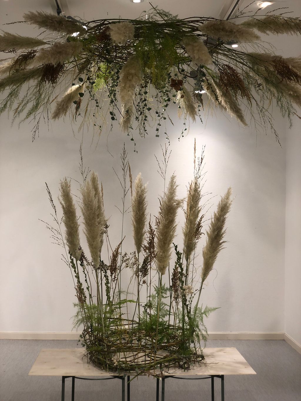 Transparent greinkrans med pampas og andre tørkede materialer. Foto.