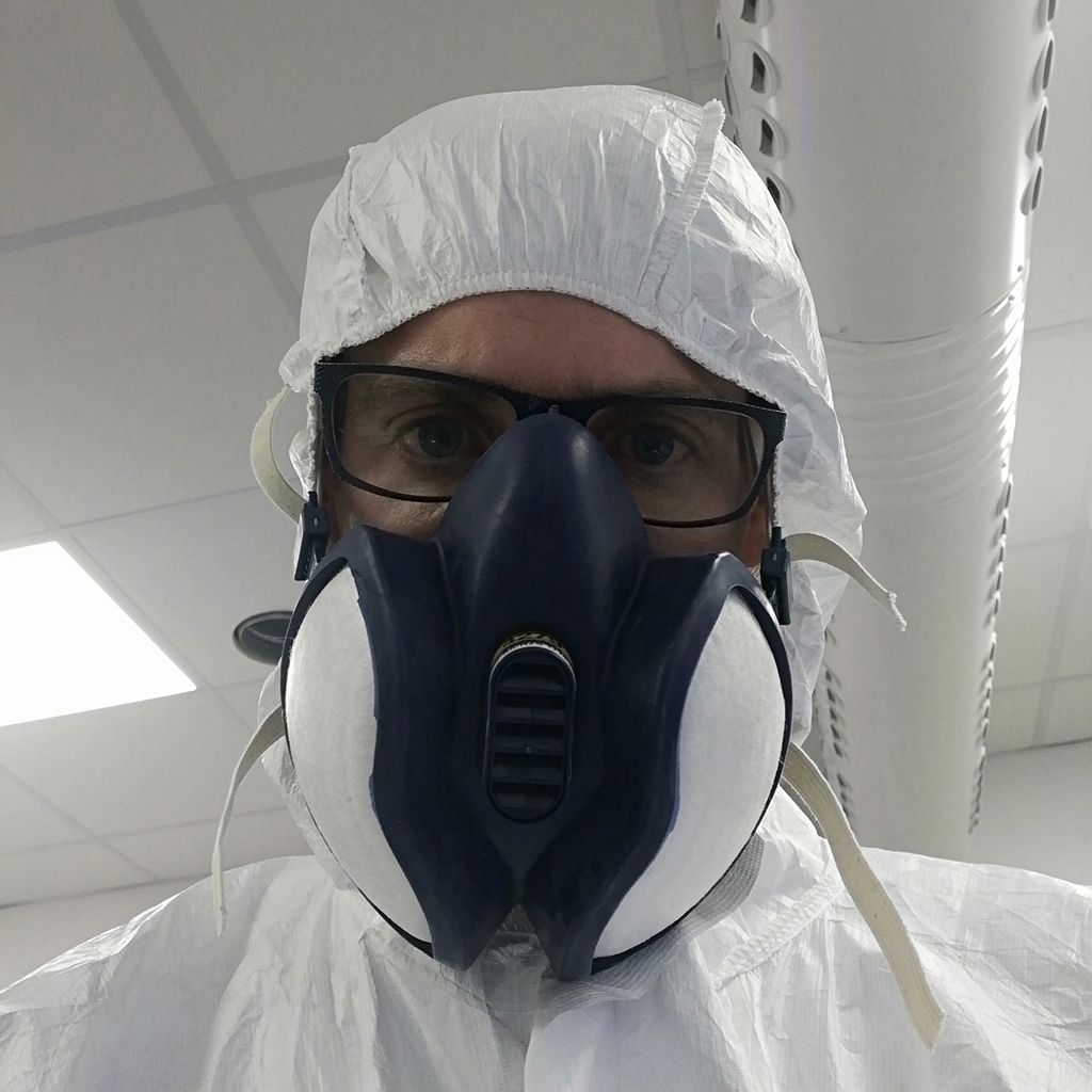 Person som har på seg vernedrakt og maske. Foto.