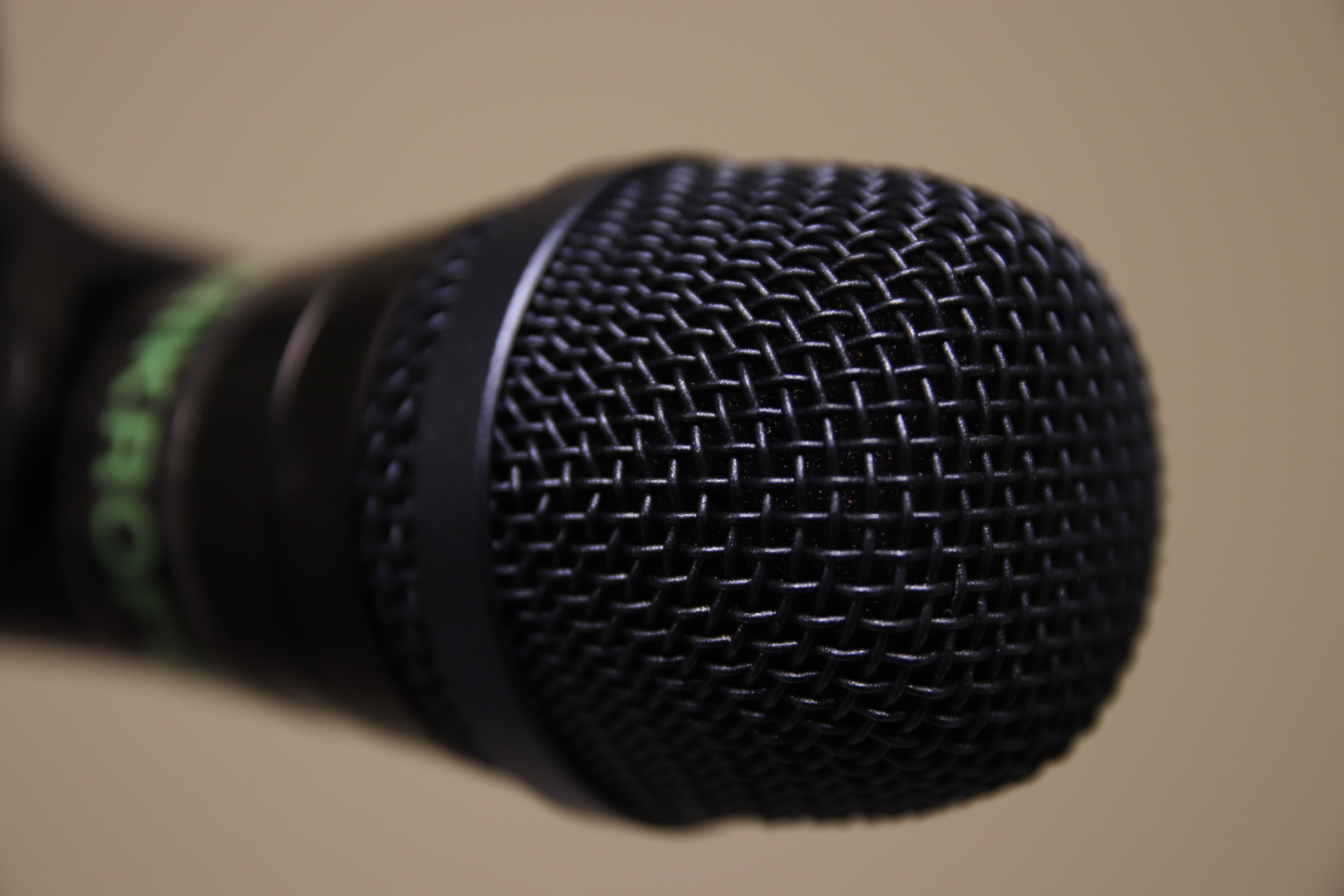 Ytterste delen av en mikrofon. Fokus er på gitteret rundt enden av mikrofonen. Resten er i ufokus. Foto.