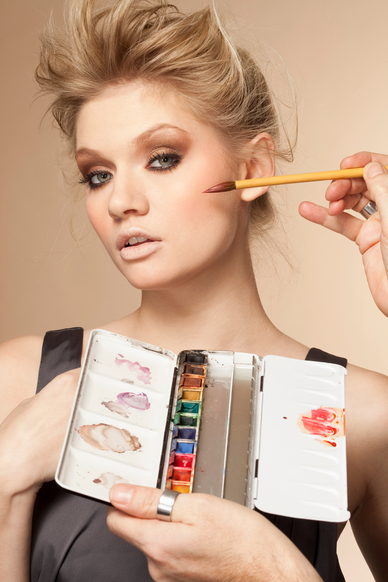 Portrett av en ung kvinne som blir sminket i studio. Foto.