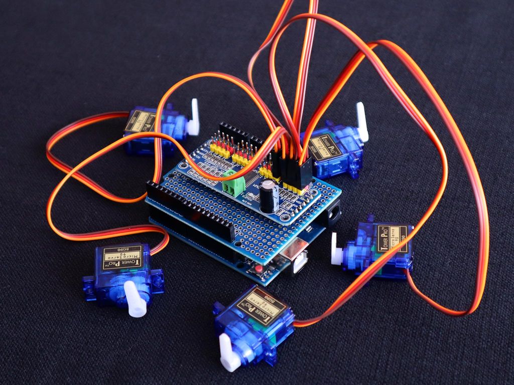 Arduino med påmontert skjold der det er tilkopla fem servomotorer. Bilde.