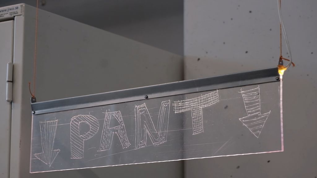 Hengende skilt med påskrift "pant" og to piler som peker rett nedover. Foto.