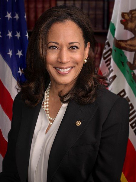 Kamala Harris er avbildet foran det amerikanske flagget og delstatsflagget til California. Foto.