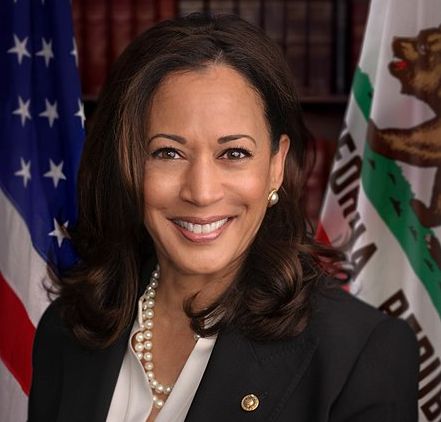 Kamala Harris standing in front of the flag of the United States of America and the state flag of California. Photo.
