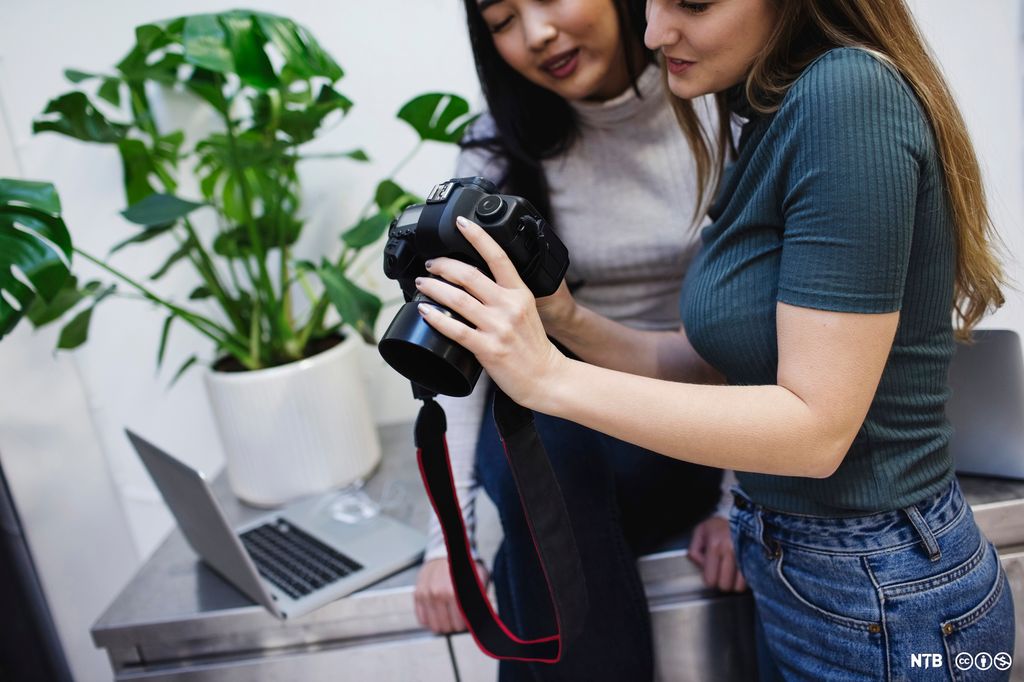 To unge kvinner som sjekker et kamera. Foto.