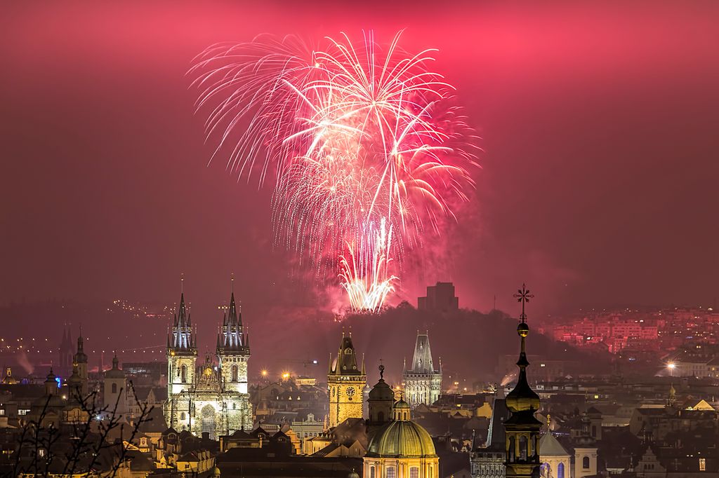 Towers and spires in Prague lit up by fireworks. Photo.