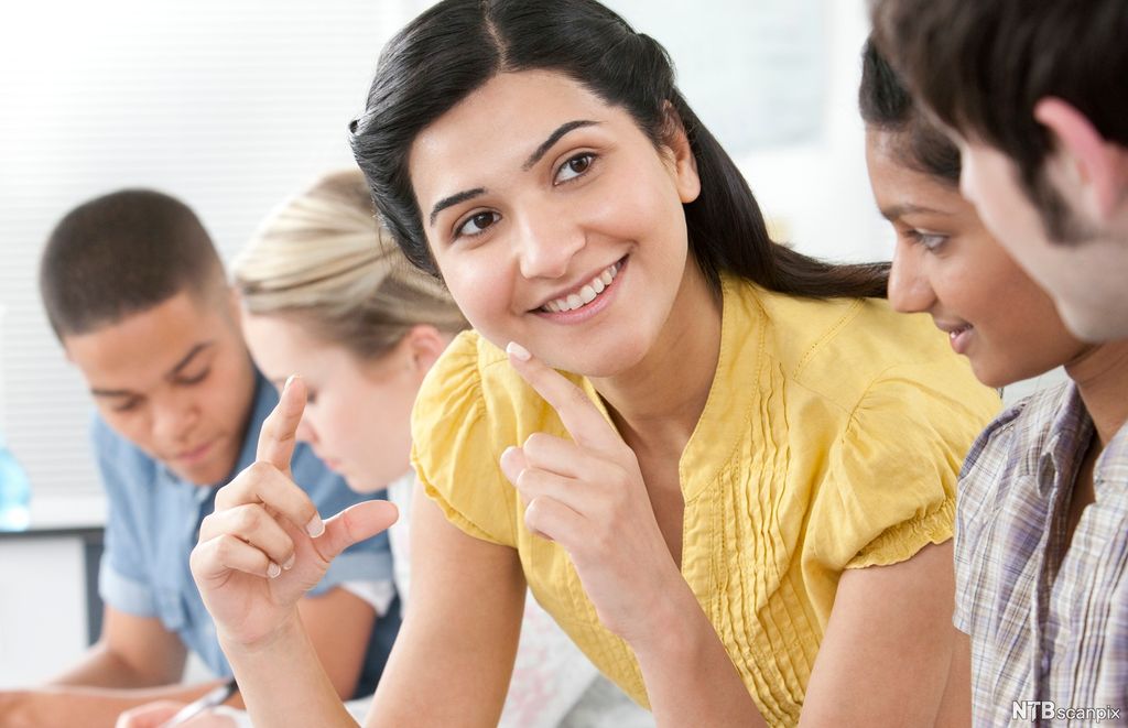 Dame forklarer til andre ved hjelp av kroppsspråk. Foto.