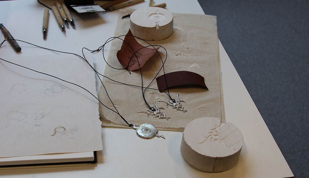 Arbeidsstasjon til tinnsmykke, ulike verktøy ligg fremme.