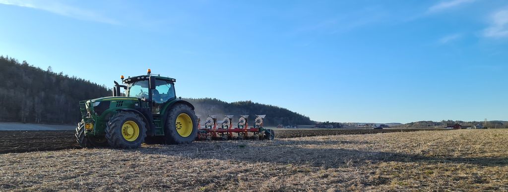 Traktor som kjører plog på et jorde. Foto.