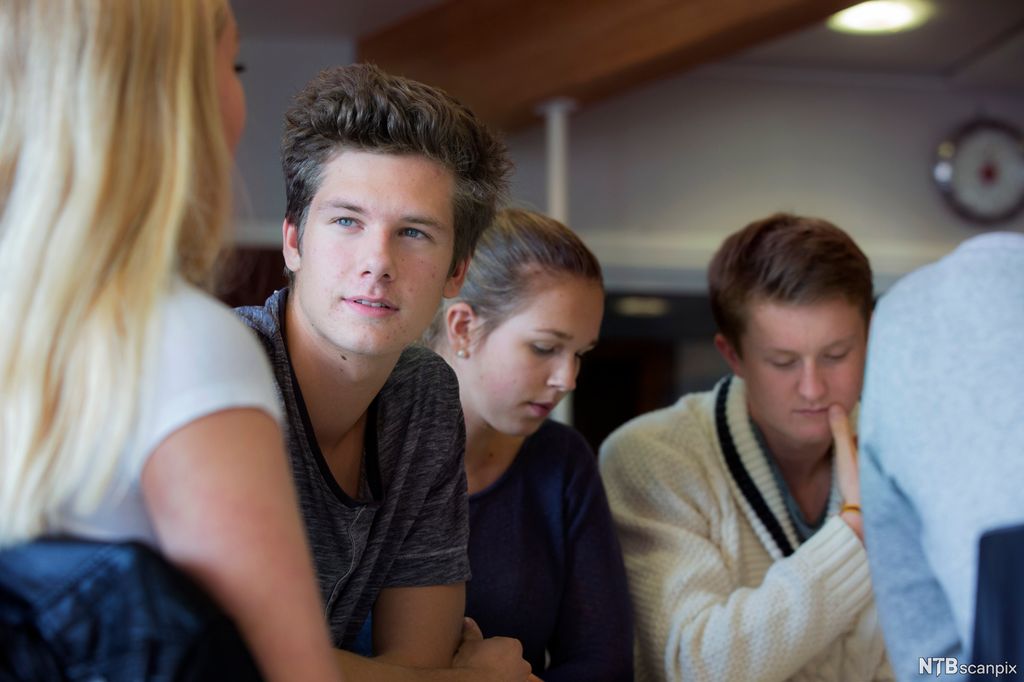 Fire elever sitter sammen i en gruppe. Foto.