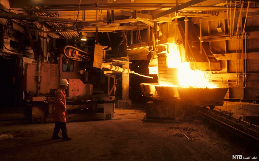 Чоловік біля плавильної печі, з яскравим полум’ям. Фото.