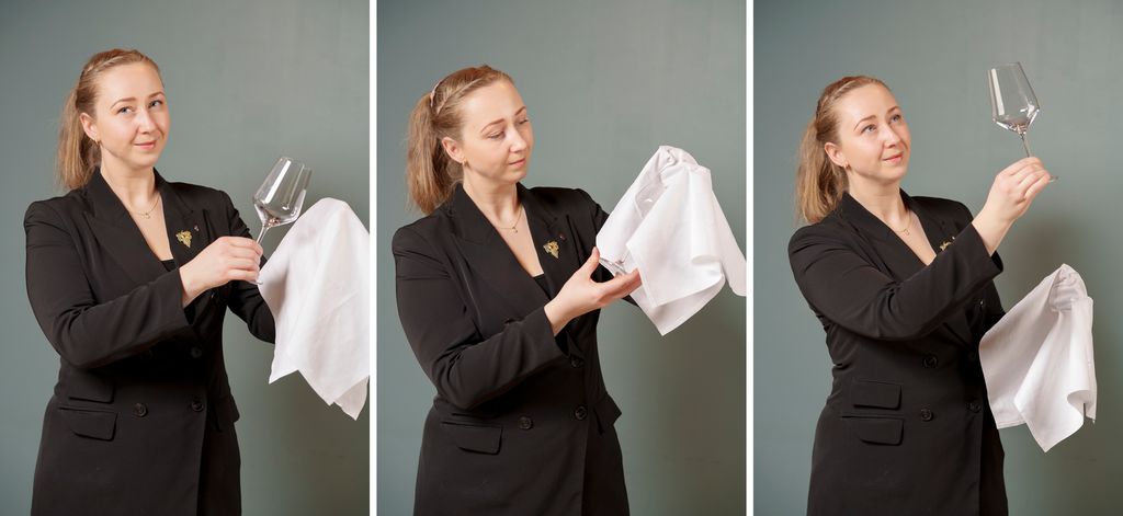 En servitør polerer vinglass med en lofri tøyserviett. Hun tar fingrene inn i servietten og fører den så inn i glassåpningen. Til slutt ser hun nøye på glasset. Foto.