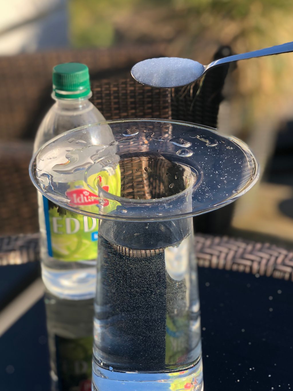 Vase med vann, sukker i en skje og en flaske eddik. Foto. 