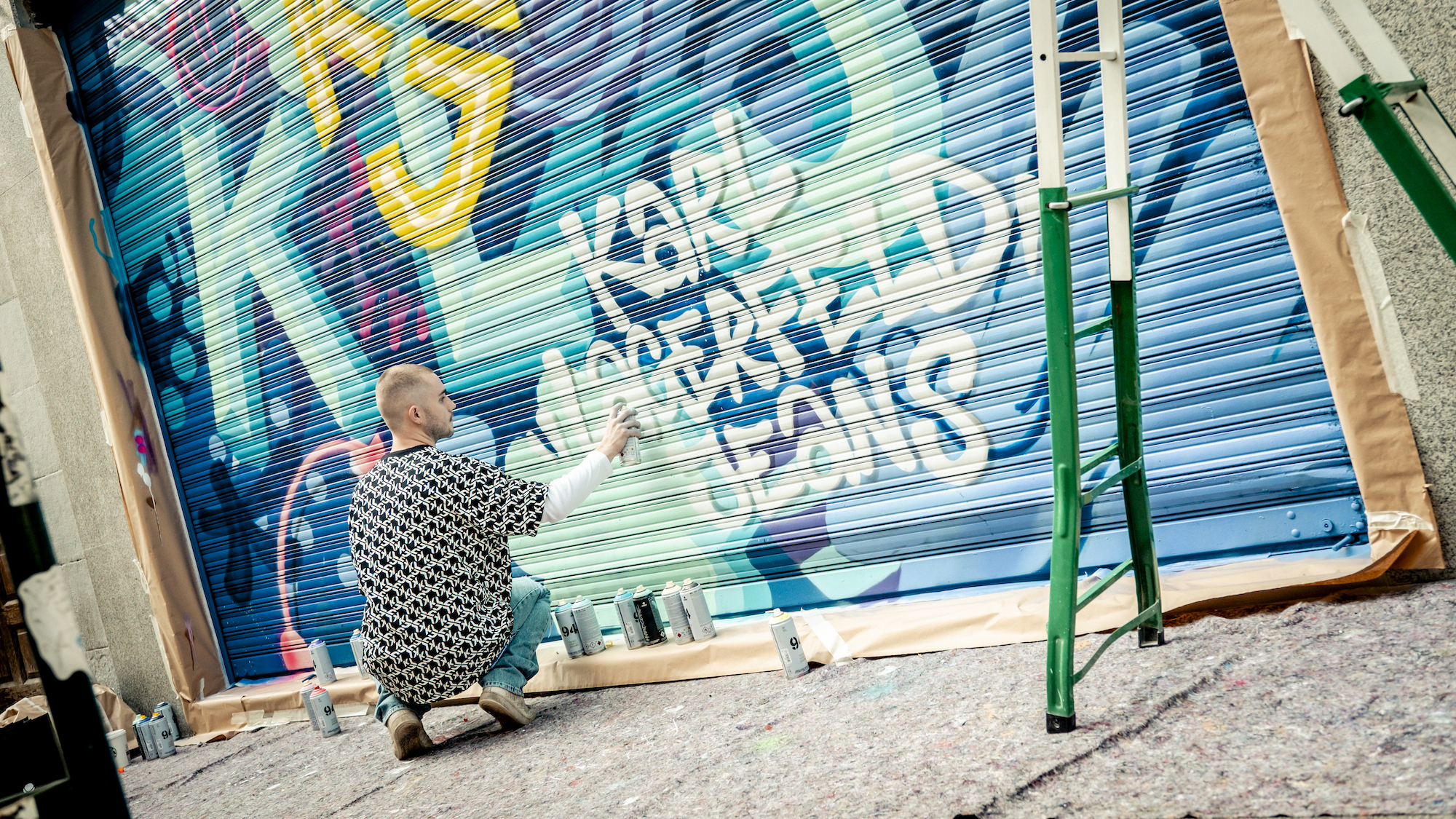 Ung mann sprayer bokstaver på en garasjeport. Foto.