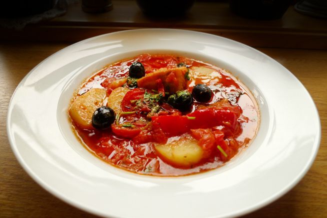 En hvit suppeskål med bacalao. Foto.