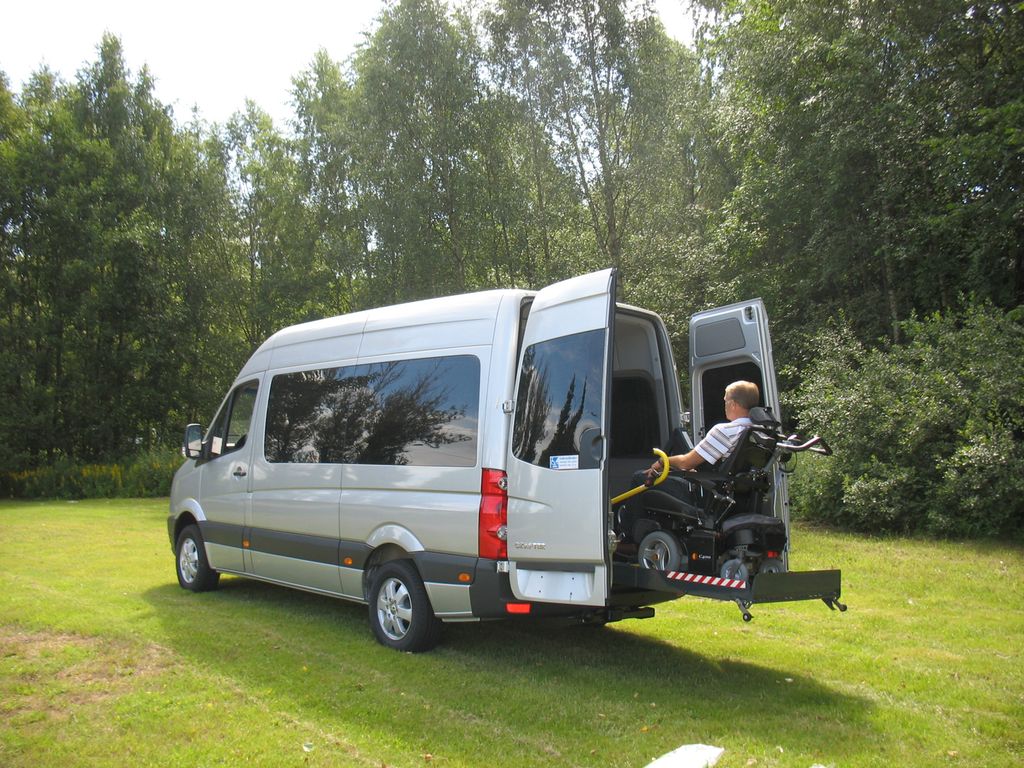 På bildet ser du en minibuss med en heis som løfter rullestolen inn. Foto.