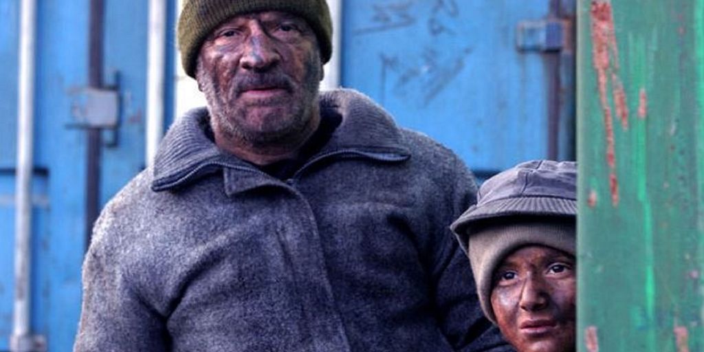 Far og son i kortfilmen Bawke. Dei er skitne og omgitt av konteinarar. Foto.