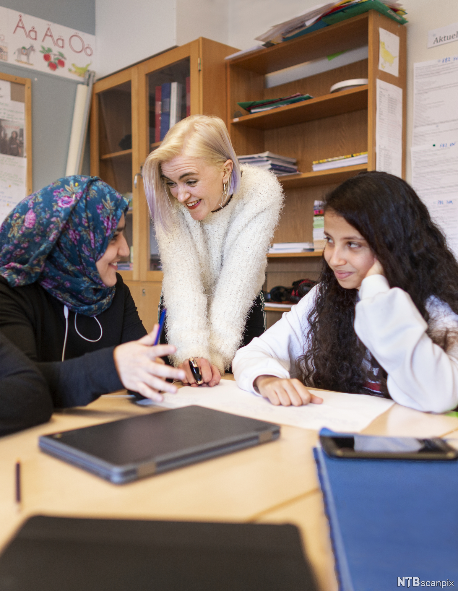 Tre personer samarbeider. Bildet viser hender, papir og en PC på et bord. Foto.
