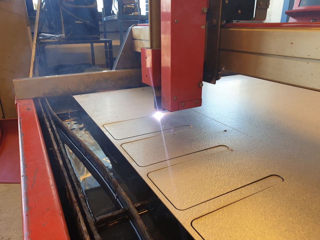 CNC-skjeremaskin med laser skjer mønster i ei plate. Foto.