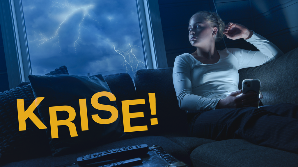 Jente sitter i sofaen i et mørkt rom. Hun snur seg og ser ut av vinduet. Utenfor lyner det. Samtidig lyser det fra telefonen som hun holder i hånden. Nede til venstre i bildet står det "Krise!" med store, gule bokstaver. Foto.
