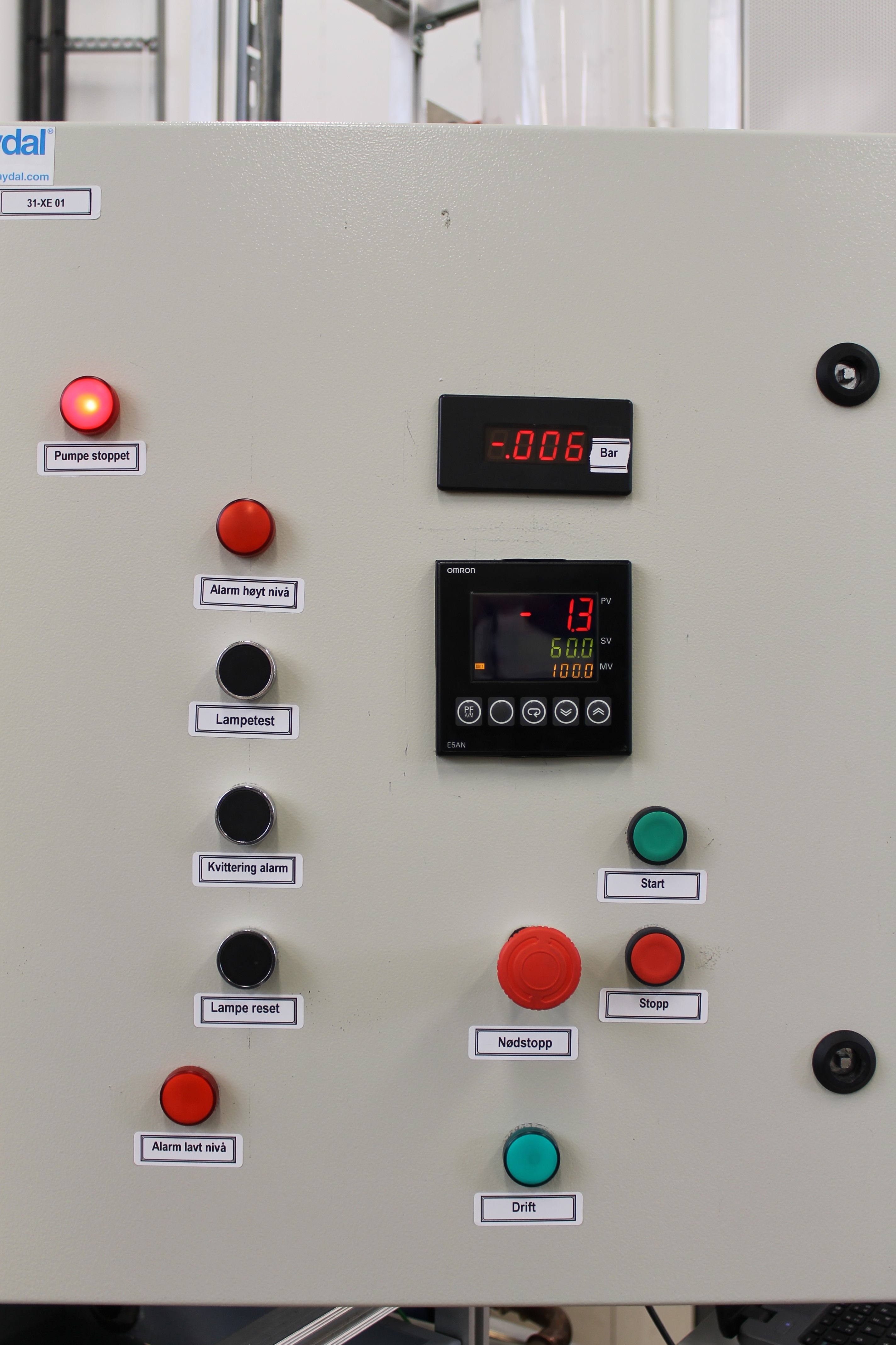 Brytarar og signallamper. Biletet viser at dei ulike lampene og brytarane har fargar som stemmer med anbefalinga i norma. Denne tavledøra har mellom anna lamper og brytarar som følgjer anbefalingane i norma: Grøn brytar startar, raude brytarar stoppar, og svarte brytarar utfører andre funksjonar. Grøn lampe betyr at pumpa er i drift, og raude lamper betyr at pumpa er stoppa, eller at ein alarm er utløyst. Foto.