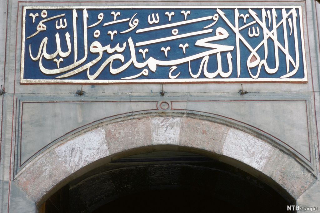 Arabisk skrift i gull på blå botn. Utsmykning over port. Foto.