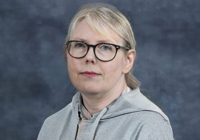 Lys kvinne med briller og alvorlig ansiktsuttrykk. Foto.