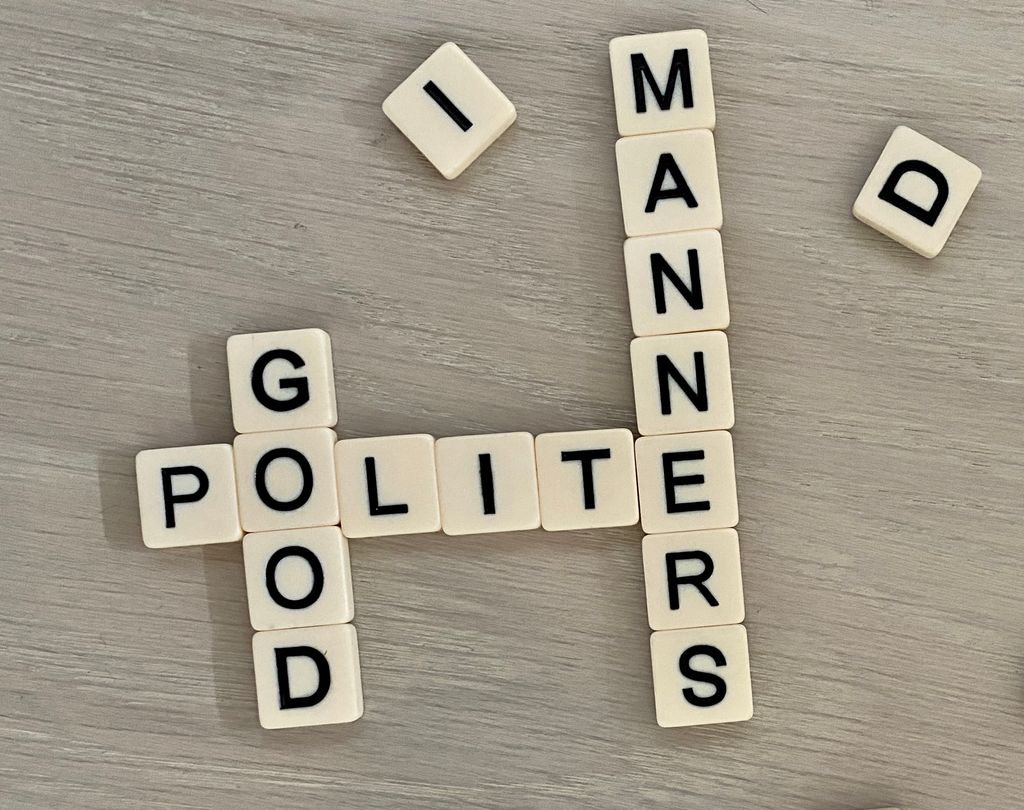 Letter tiles spelling out the words polite, good, and manners. Photo.