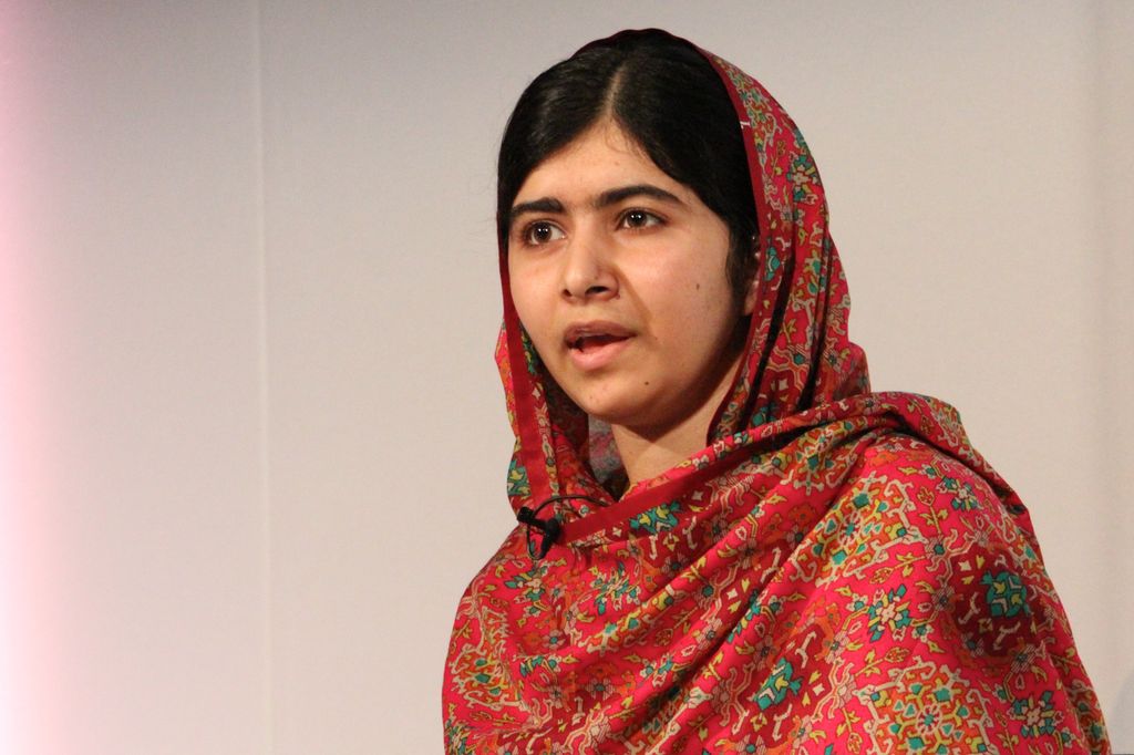 Malala Yousafzai dressed in a patterened, orange shawl. Photo.