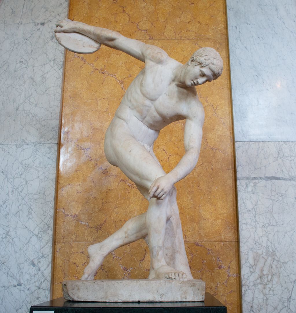 Marmorstatue av ein naken mann som kastar diskos. Foto.