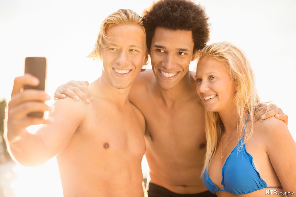 Tre ungdommer i badedrakt tar en selfie. Foto.