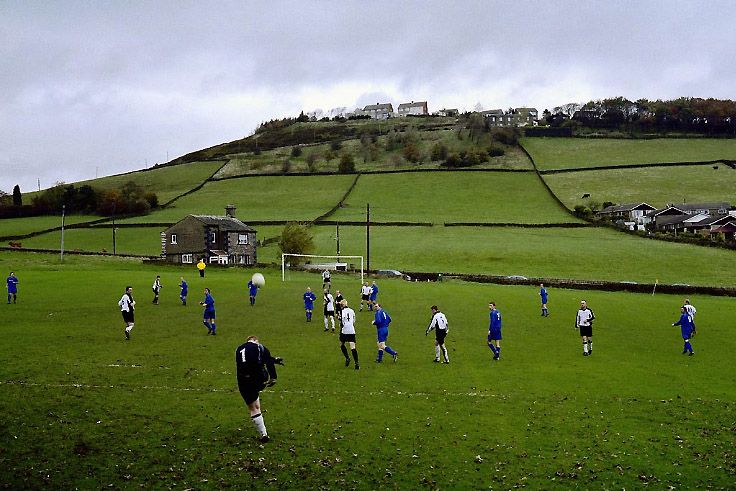 A football match played on a field in a rural part of England. Photo.