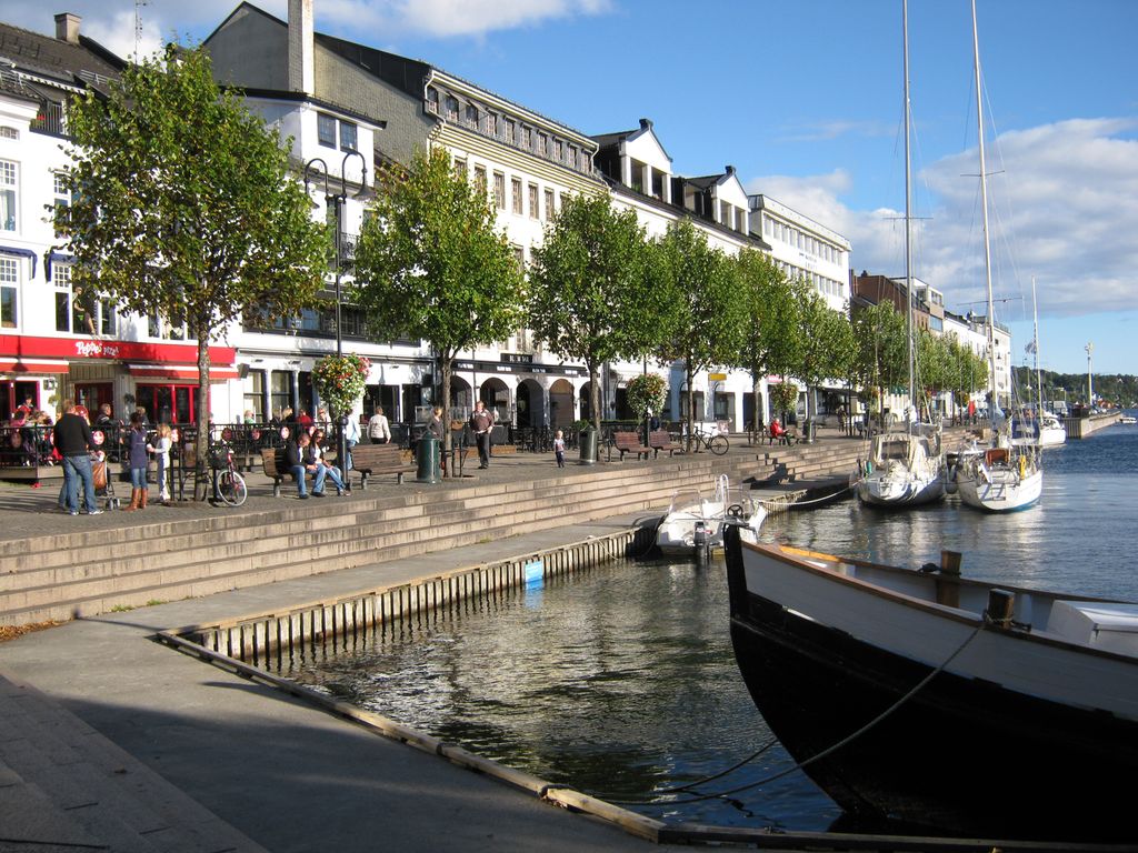 Båtar, restaurantar og menneske på bryggja. Foto.