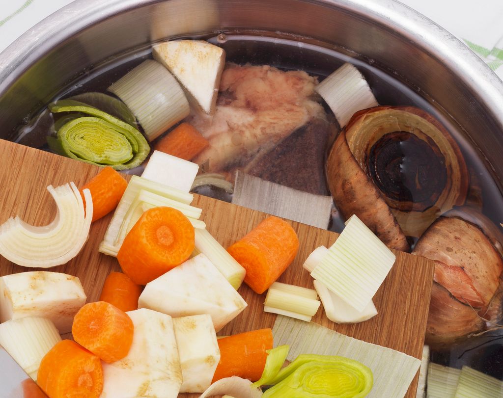 Oppkutta grønsaker på veg frå skjerefjøl til kjele med vatn. Foto.