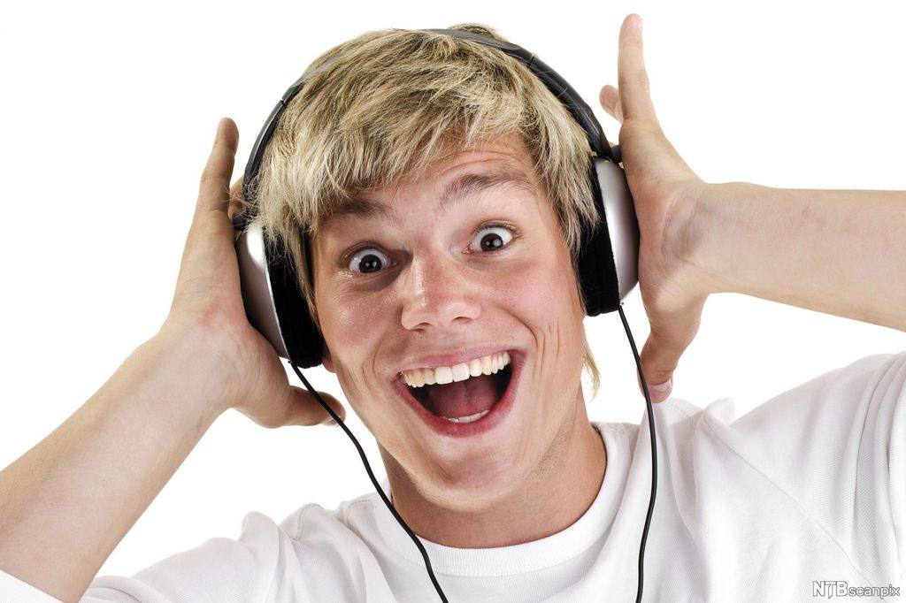 Gutt som lytter på høy musikk gjennom øretelefoner. Foto.