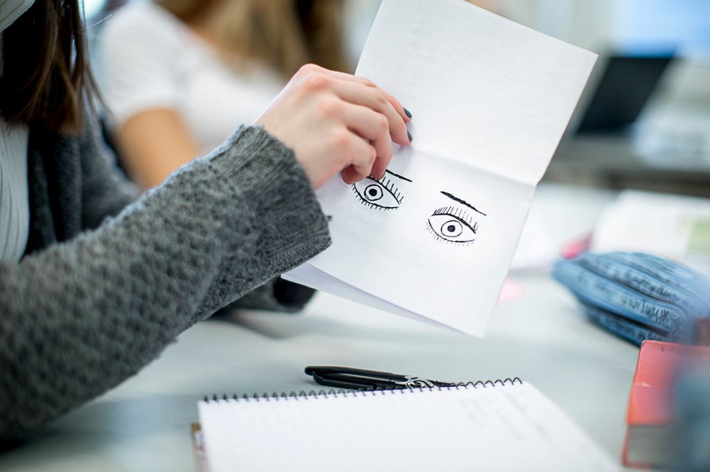 Ei jente holder opp en tegning av to øyne. Foto.