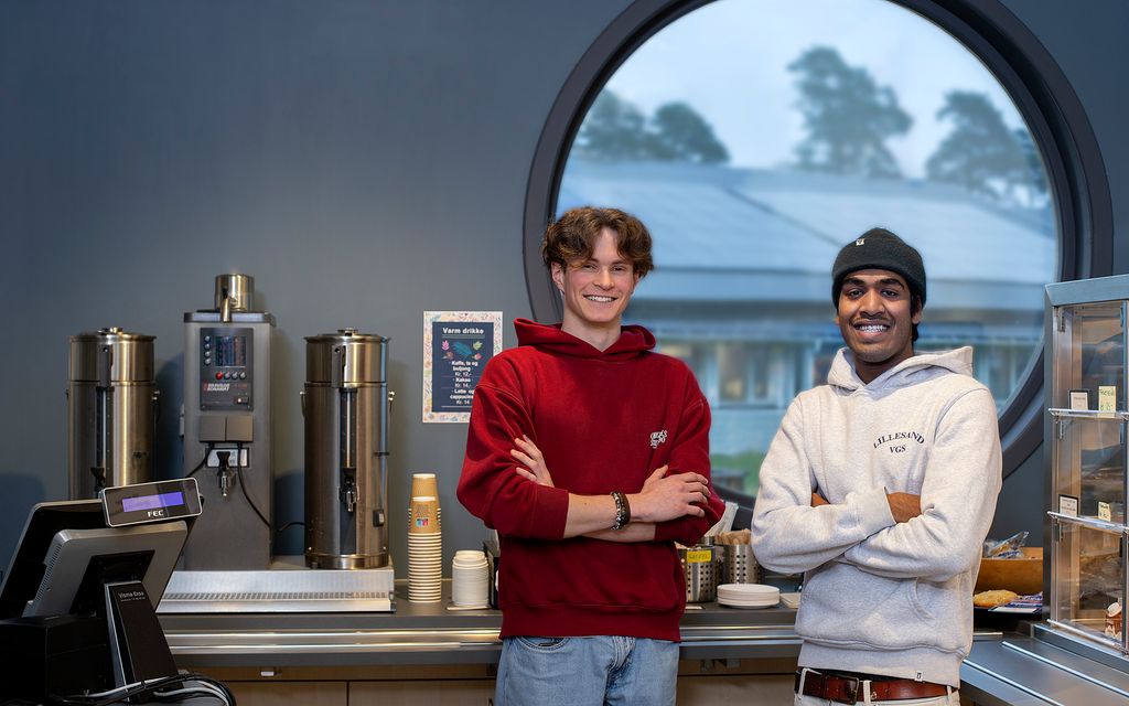 Enkel kaffebar med to gutter stående ved siden av kaffemaskinen. Foto.