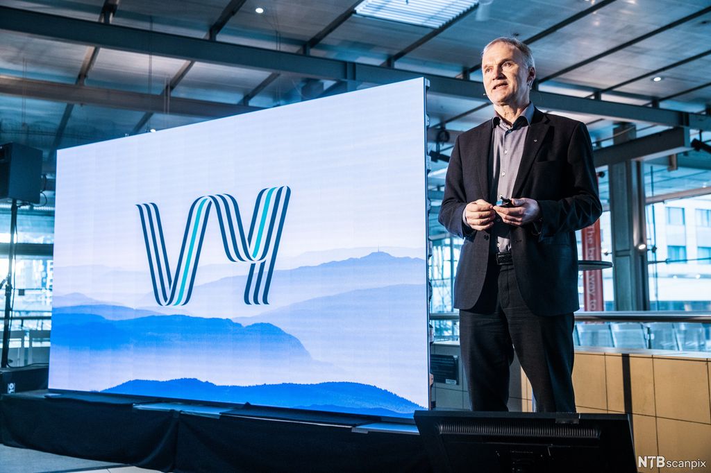 Konsernsjef Geir Isaksen ved siden av tavle med logoen til Vy. Foto.