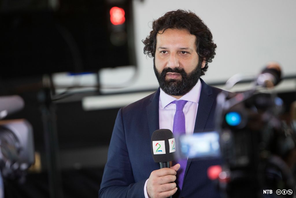 Journalist Kadafi Zaman står med TV 2-mikrofon. Foto.