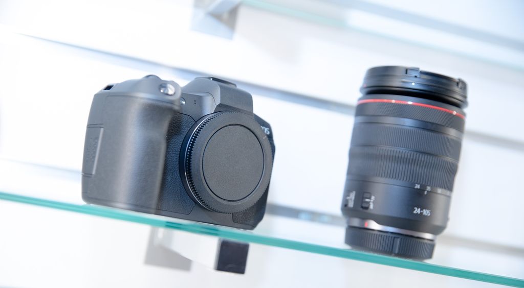 Speilreflekskamera og et objektiv utstilt på en glasshylle. Foto.
